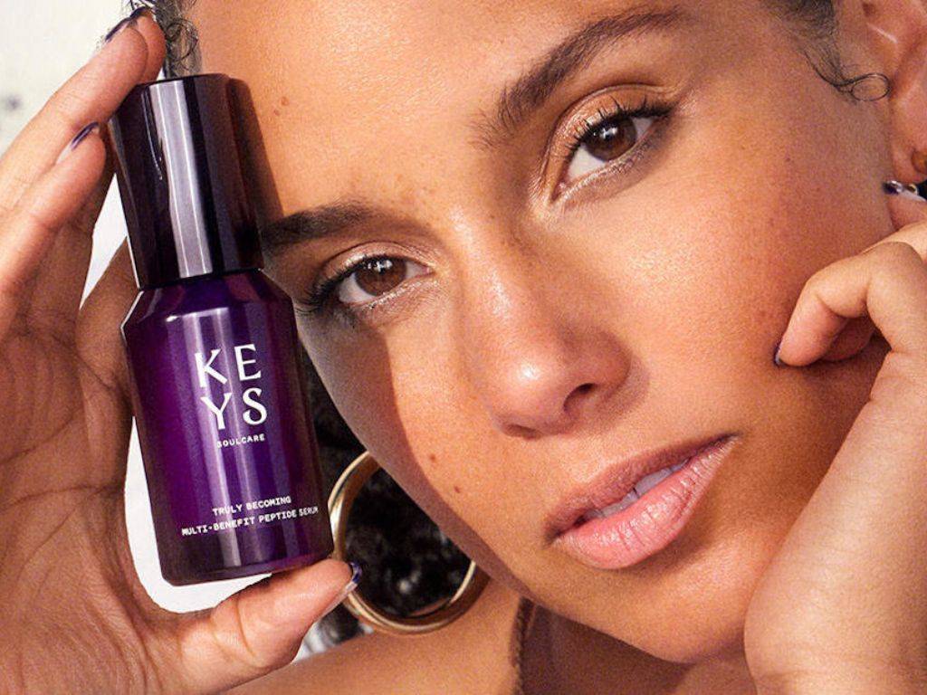 Na obrázku je zobrazená Alicia Keys pri prezentácii svojej línie wellness produktov KEYS Soul Care, ktorá sa zameriava na starostlivosť o dušu a telo. Alicia, známa svojím zápalom pre duševné a fyzické zdravie, sa nachádza v prostredí plnom prírodných prvkov, čo podčiarkuje filozofiu jej značky. S jemným a upokojujúcim výrazom tváre vyžaruje pokoj a rovnováhu, čo reflektuje aj produkty v pozadí, ako sú aromatické oleje, krémy a esenciálne masti. Atmosféra obrázka evokuje harmóniu, relaxáciu a zameranie na vnútorný pokoj. Alicia v oblečení, ktoré kombinuje pohodlie s eleganciou, zobrazuje hodnoty svojej značky, ktorá podporuje starostlivosť o seba, zmyslový zážitok a pozitívnu energiu. KEYS Soul Care je viac než len produkt; je to cesta k osobnej pohode, ktorá sa zameriava na starostlivosť o dušu, telo a myseľ. Obrázok zachytáva filozofiu autenticity a spojenia so sebou samým.