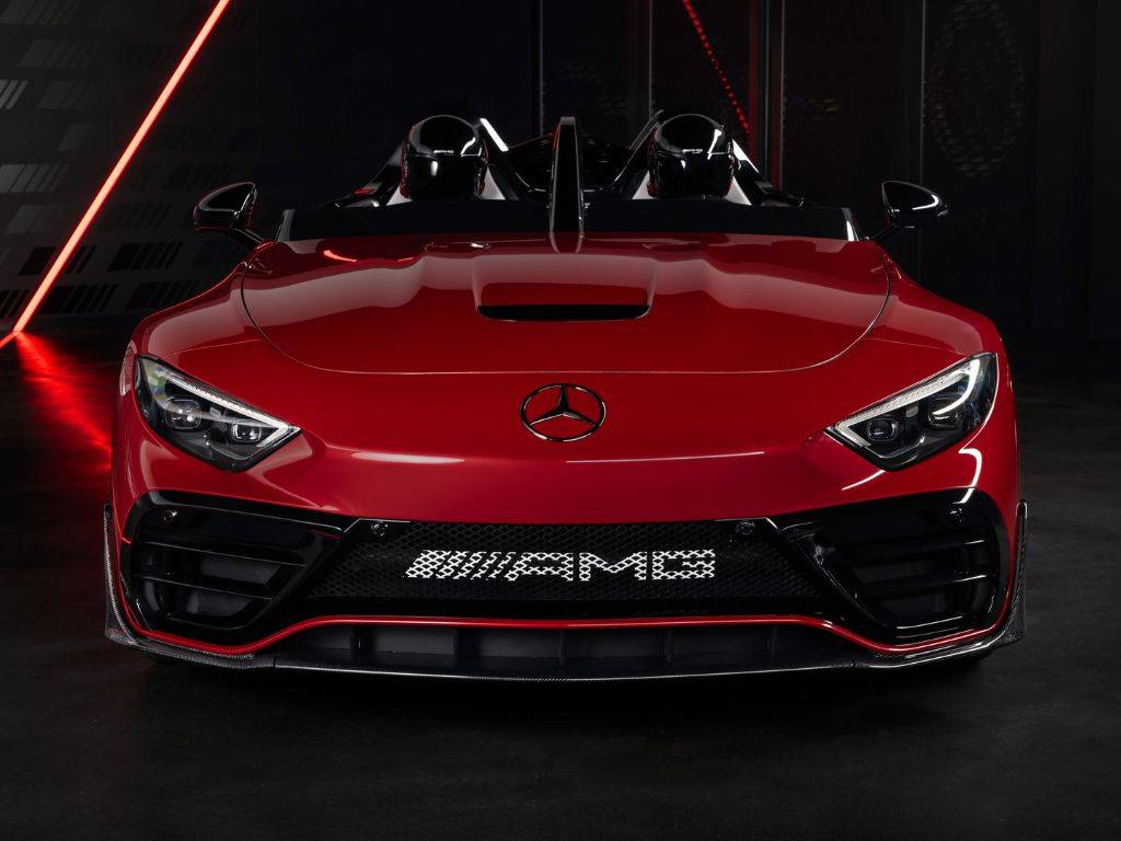 Červené športové auto Mercedes-AMG PureSpeed zaparkované na otvorenej ceste, s aerodynamickým dizajnom, ikonickou prednou maskou a elegantnými detailmi.